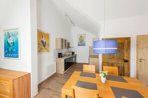 Una cocina compacta con electrodomésticos modernos, una zona de comedor con mesa y sillas de madera, y una puerta de madera.
