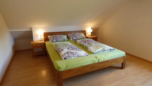 Ein Einzelbett mit Holzrahmen, zwei Nachttische und ein Beistelltisch mit Lampe.