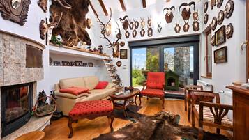 A room with a fireplace, a sofa, a red armchair, and a dining table.