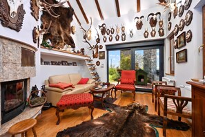 A room with a fireplace, a sofa, a red armchair, and a dining table.