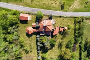 An aerial view of a house with a red roof, surrounded by greenery and a road. - Hunting Lodge Hills Retreat, Ribnjačka, Croatia (Ribnjačka)