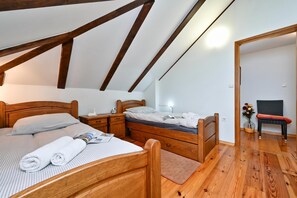 A bedroom with a sloped ceiling, wooden beams, a bed with pillows, a nightstand, a dresser, and a chair. - Hunting Lodge Hills Retreat, Ribnjačka, Croatia (Ribnjačka)