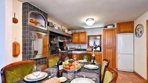 A dining area with a table set for four, surrounded by chairs, with a kitchen in the background.