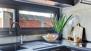 Een koelkast, een oven, een kookplaat, kookgerei, borden en bestek