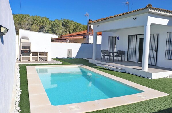Enjoy outdoor dining or relaxation by the pool surrounded by a well-maintained lawn and patio.
