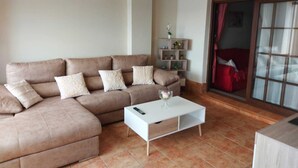 A living room with a brown sectional sofa, a white coffee table, and a red chair. - Apartment Los Pelicanos (Ayamonte)