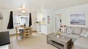 A modern living room with a sofa, coffee table, and dining area with chairs and a table. - Quiet, Charming, Great Value @ Beach w/ AC (Newport Beach)