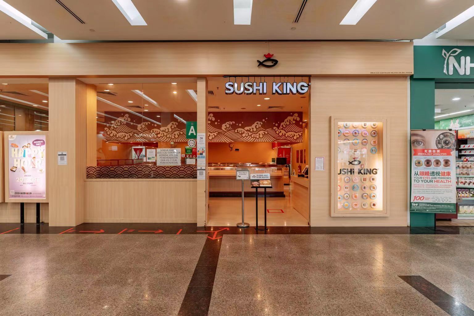 De ingang van een sushi restaurant genaamd Sushi King, met een traditioneel Japans interieur, een toonbank en een zitgedeelte.