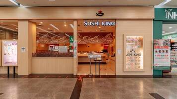 De ingang van een sushi restaurant genaamd Sushi King, met een traditioneel Japans interieur, een toonbank en een zitgedeelte.
