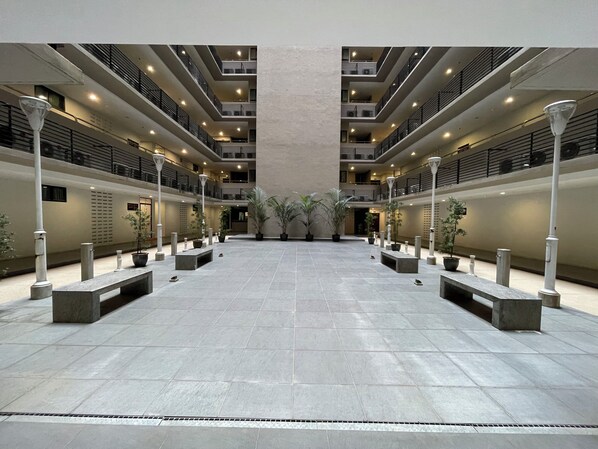 A spacious atrium with a central open area, multiple levels with balconies, and potted plants. - Super Comfy 1800sqft Condo, 3bedroom with 2kingsize bed in Kuching, Sarawak (Kuching)