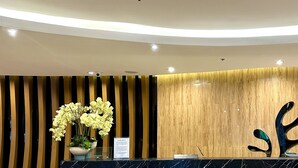 A reception area with a curved wooden reception desk, a vase of yellow flowers, and a privacy notice sign. - Mall of Asia Shore 2 (Pasay)