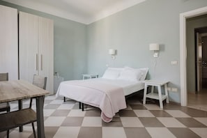 A bedroom with a bed, bedside tables, a wardrobe, and a table with chairs. - Cavour 96 Apartment in Firenze (Florence)