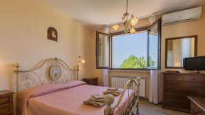 A bedroom with a bed, a dresser, a television, and a window with a view. - Leondina Country House with pool and panoramic view in Corinaldo, a heaven of peace in the Marche co (Corinaldo)