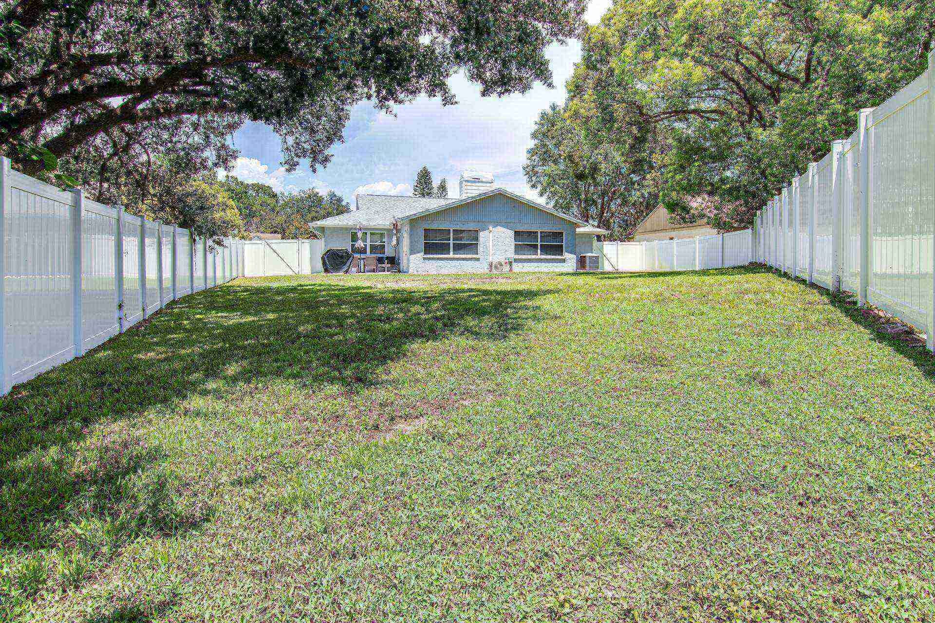 A house with a sloped roof, a front porch, and a fenced backyard.