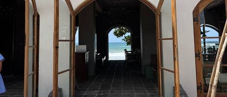 A hotel entrance with arched wooden doors leading to a beach view.