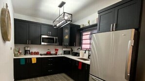 A compact kitchen with dark cabinets, a stainless steel refrigerator, and a microwave.