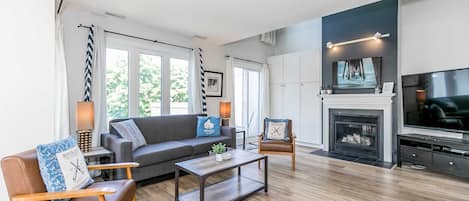 Una sala moderna con sofá, sillones, una mesita de centro, chimenea y televisor.