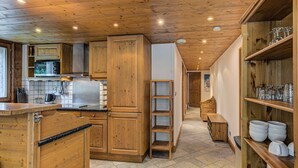 A wooden interior with a kitchen area, including cabinets, a microwave, and a coffee machine.