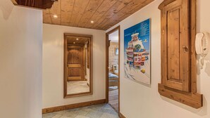 A wooden hallway with a door, a poster, and a telephone on the wall.