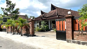 A traditional building with a tiled roof, brick walls, and a gated entrance. - Capital O 92615 Villa Utama D'alas Purwo (Kendalrejo)