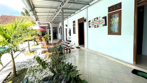 A covered walkway with a tiled floor, benches, and potted plants. - Capital O 92615 Villa Utama D'alas Purwo (Kendalrejo)