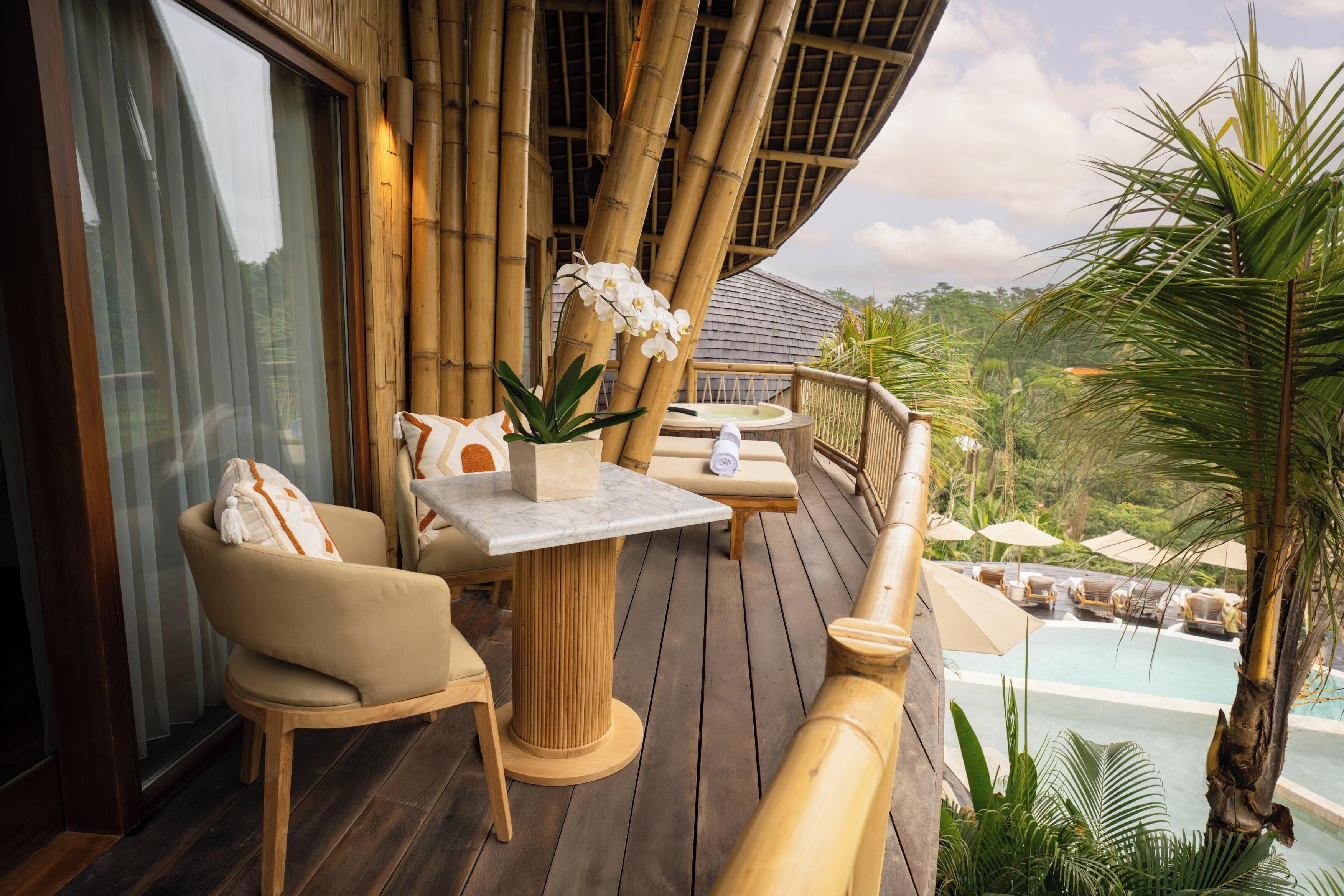 A wooden deck with a table and chairs, a hot tub, and a pool area.