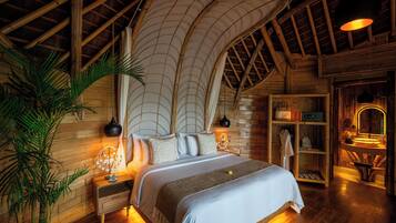 Une chambre spacieuse avec un grand lit, des murs en bois, un plafond voûté et une table de chevet avec une lampe.