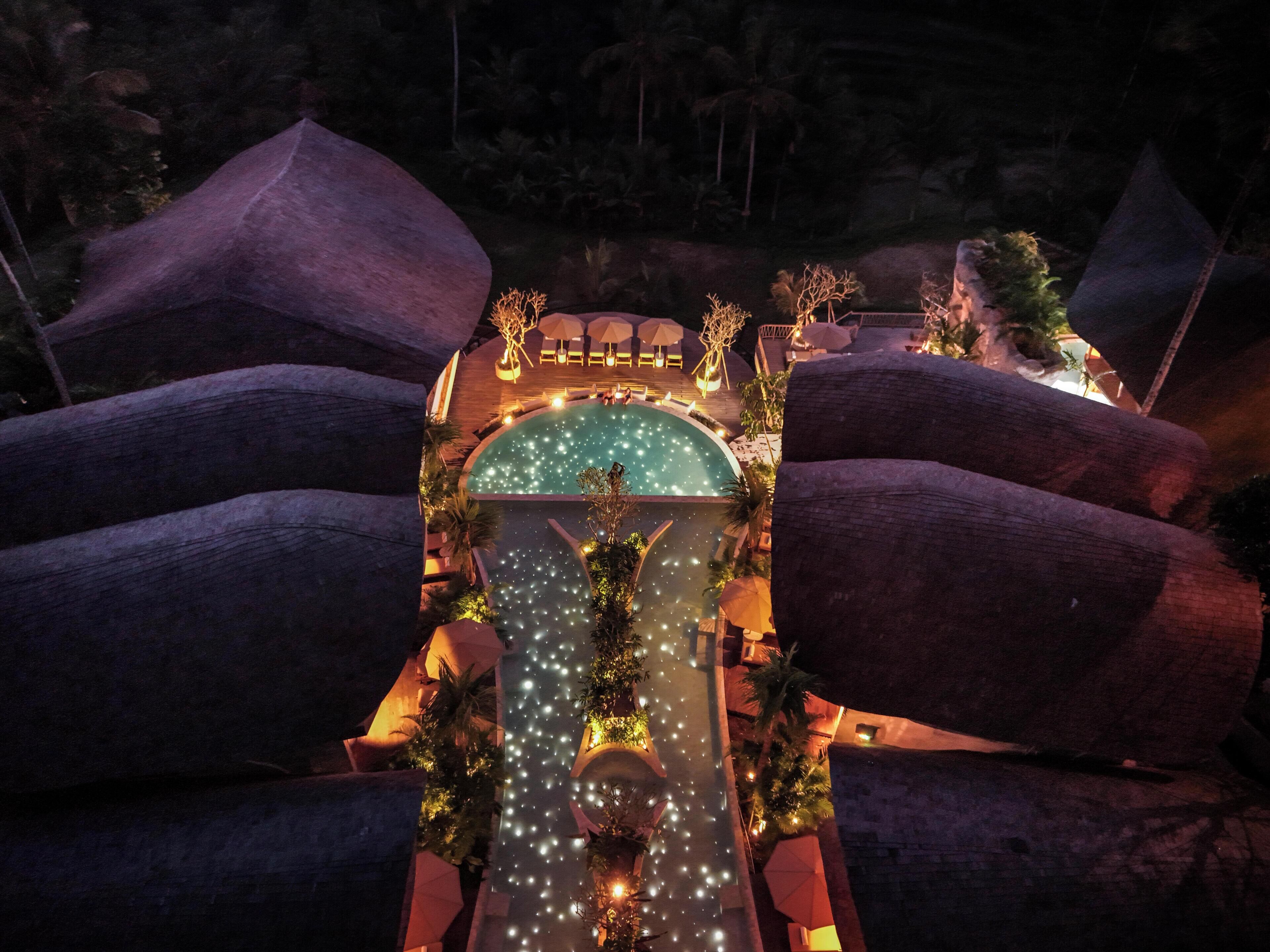 A pool with a waterfall feature, surrounded by large rocks and outdoor seating areas.