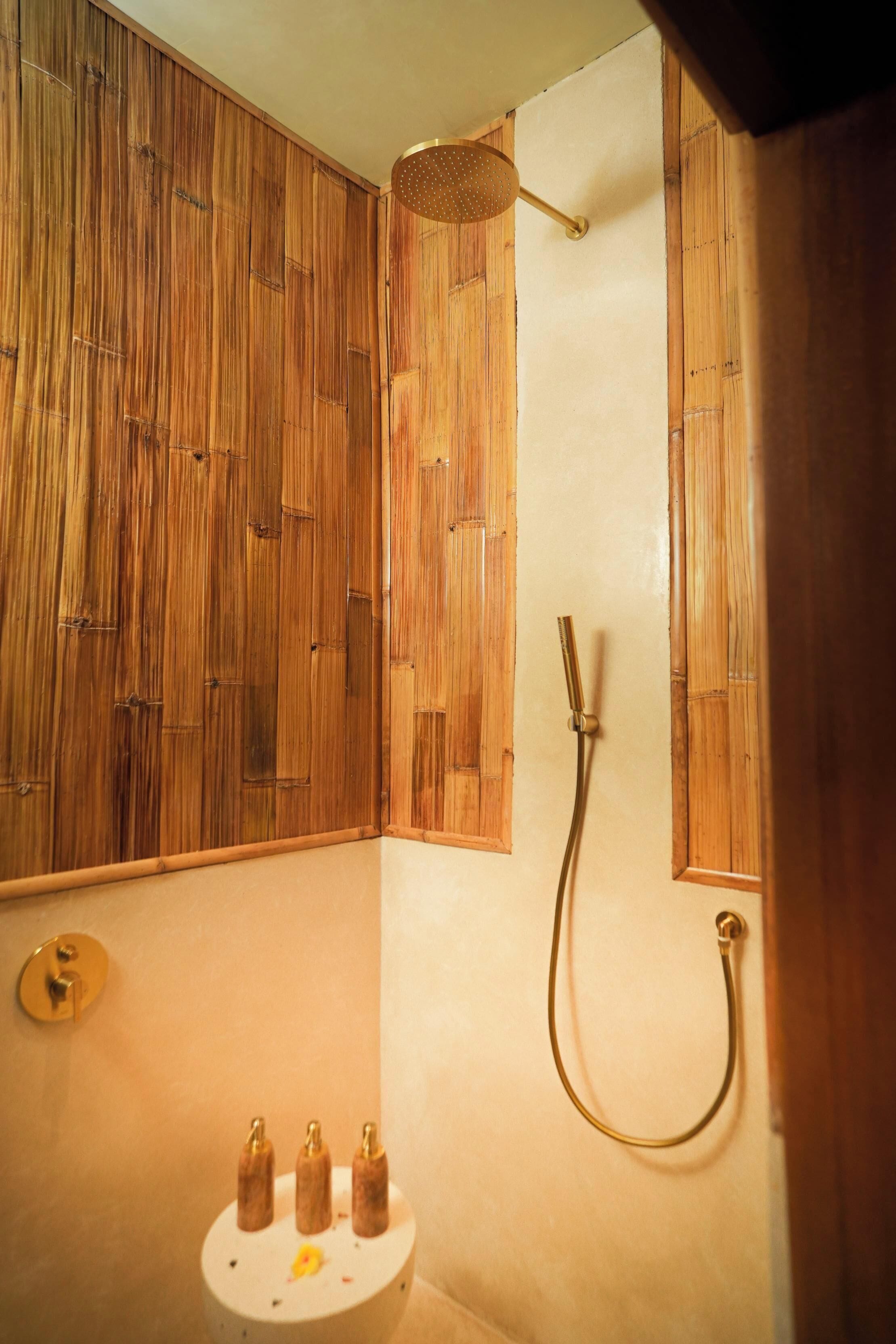 Een badkamer met houten lambrisering, een douche met handdouche en een toilet met een bidet.