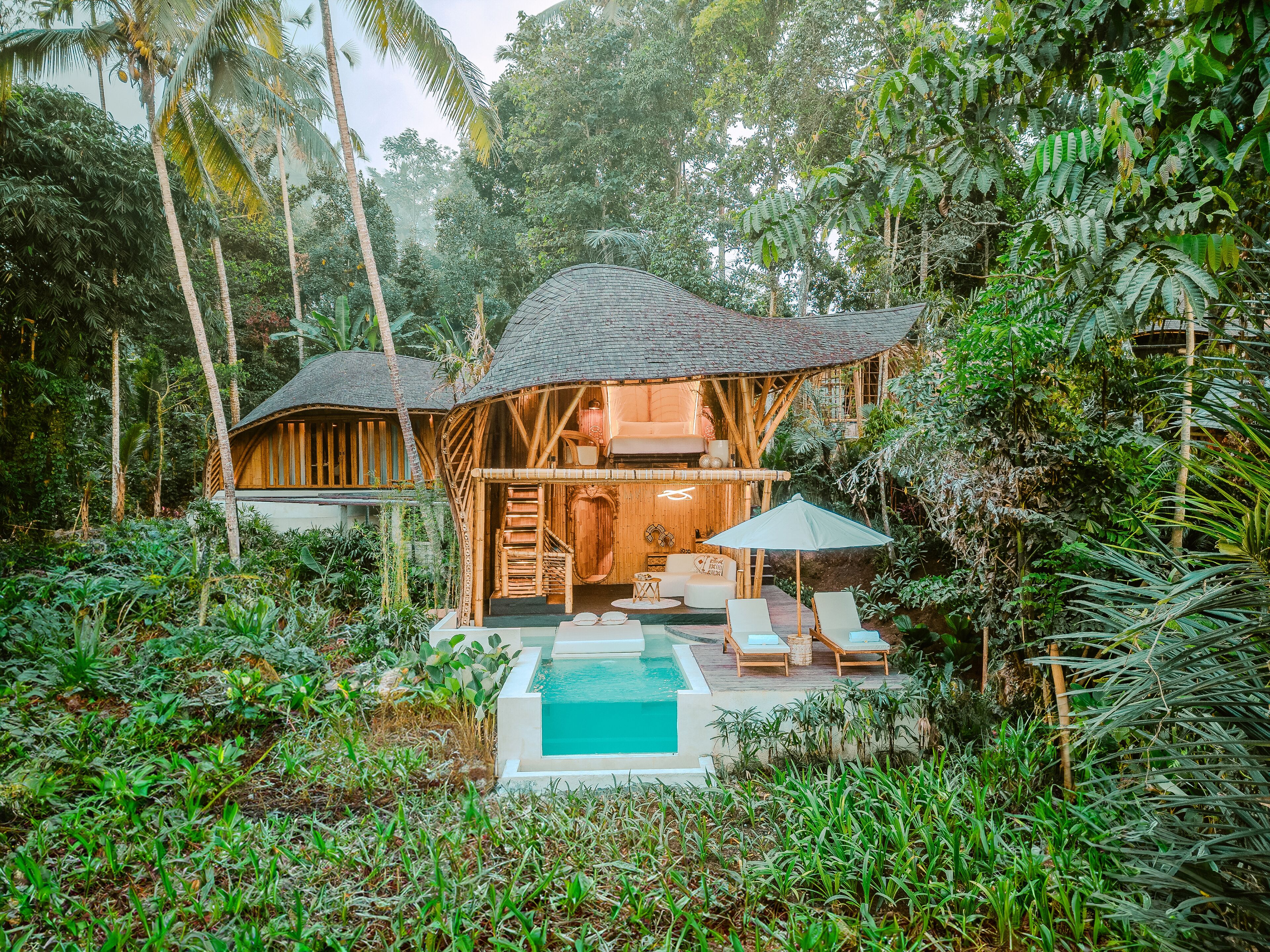 Un resort tranquilo y ecológico con una estructura central de madera, piscina privada y exuberantes paisajes tropicales.