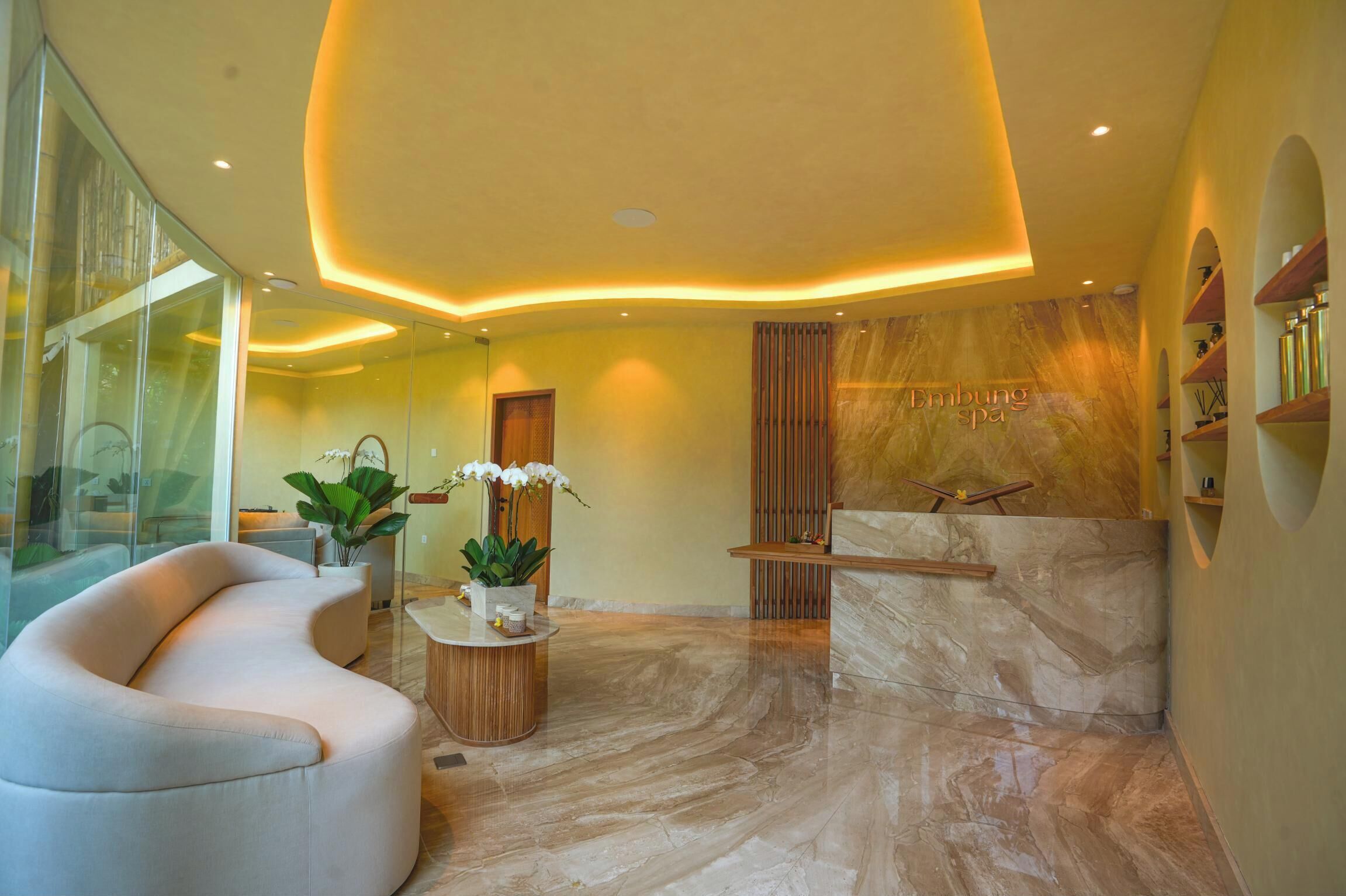 A modern spa lobby with a curved seating area, a reception desk, and a marble floor.