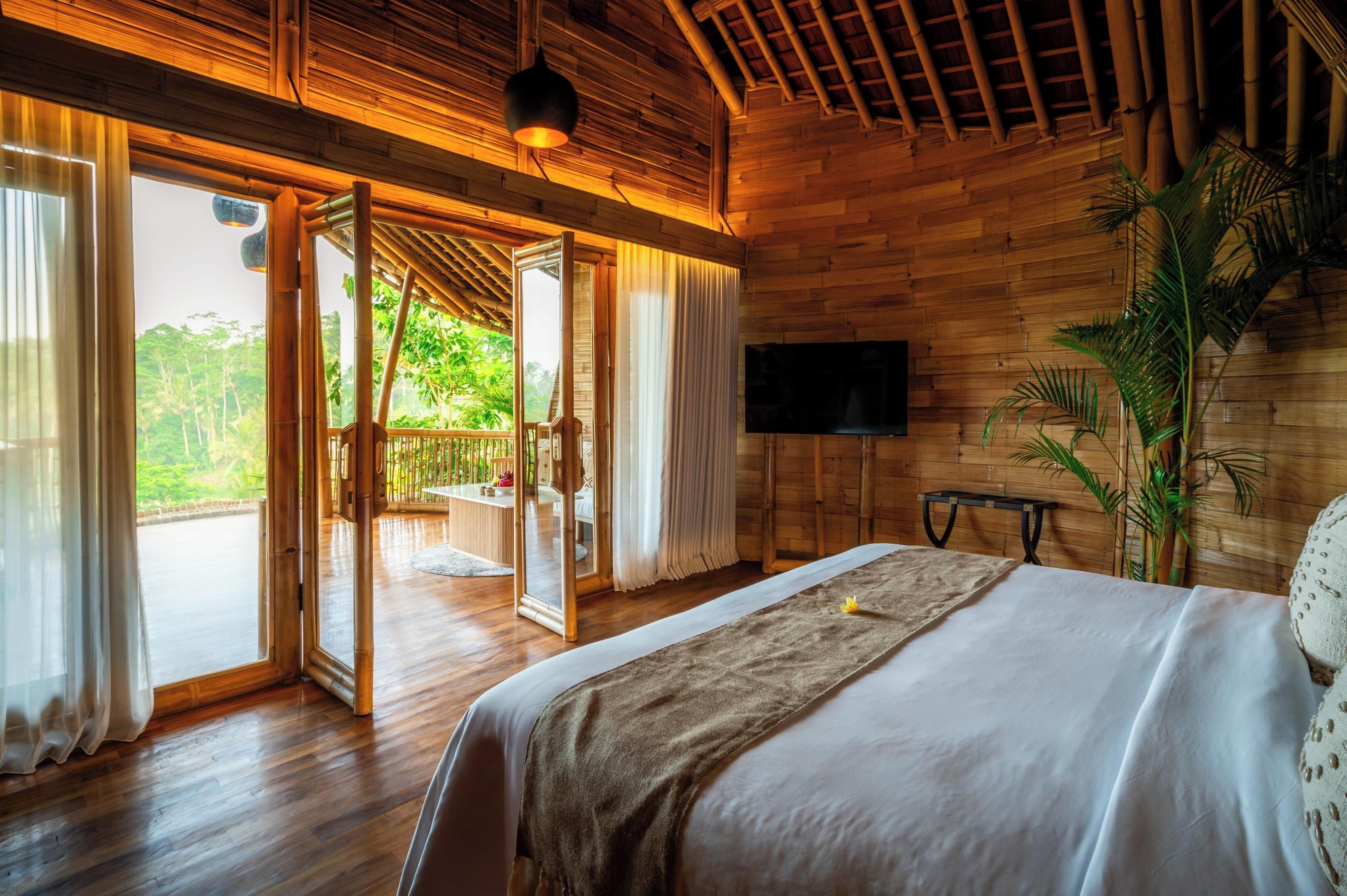 Quarto de madeira com cama, televisão e uma grande janela.