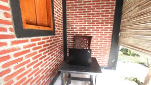 A corner with a brick wall, a wooden chair, and a table. - Hotel O Mareje Sariguna (Mataram)