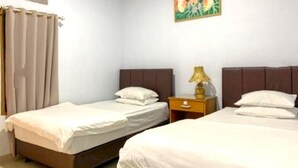 A room with two single beds, a nightstand with a lamp, and a painting on the wall. - Hotel O Mareje Sariguna (Mataram)