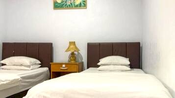 Camera d'albergo con due letti, un comodino con una lampada e un quadro appeso al muro.