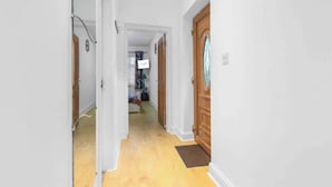 A hallway with white walls, wooden doors, and a yellow floor.