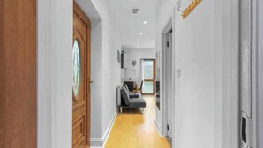 A hallway with a wooden door, a grey sofa, and a white wall.