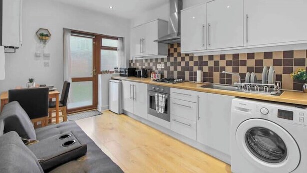 A modern kitchen with grey cabinets, a built-in oven, a microwave, and a dishwasher.