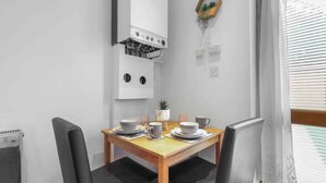 A compact kitchen with a stove, a small refrigerator, and a dining table with chairs.