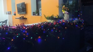 Une pièce avec un mur orange, un téléviseur, une petite étagère et une fenêtre.