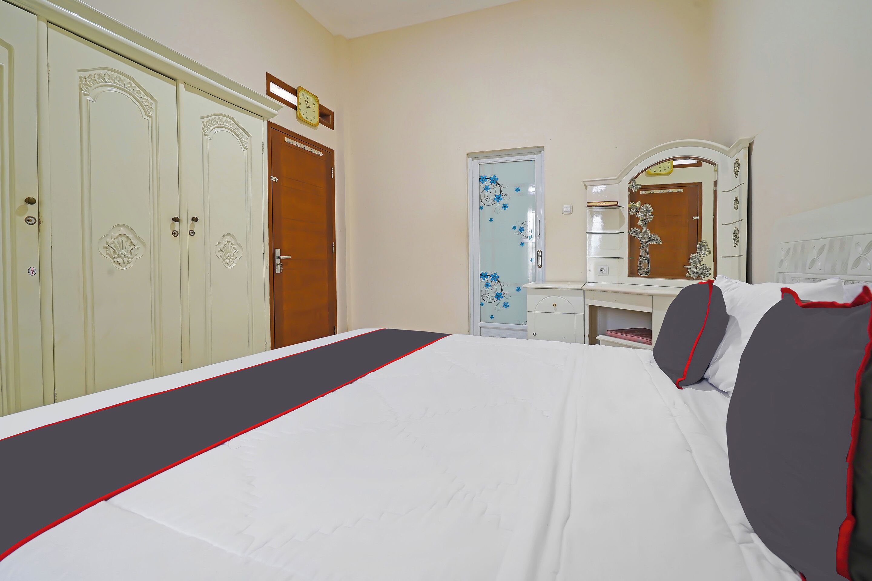 Een hotelkamer met een bed, een kledingkast, een spiegel en een deur versierd met bloemen.