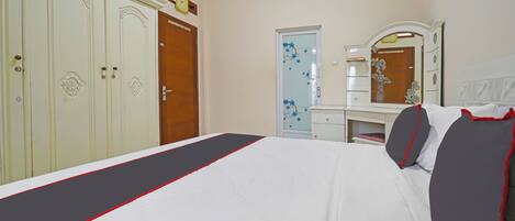 A hotel room with a bed, a wardrobe, a mirror, and a door with floral decorations.