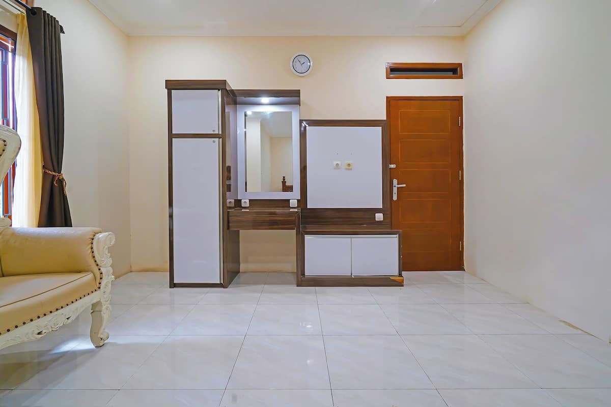 A room with a sofa, a wardrobe, a mirror, a clock, and a door.