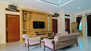 A spacious living room with a large flat-screen TV, two sofas, and a wooden entertainment unit. - Collection O 92634 Villa Ds (Rancakalong)