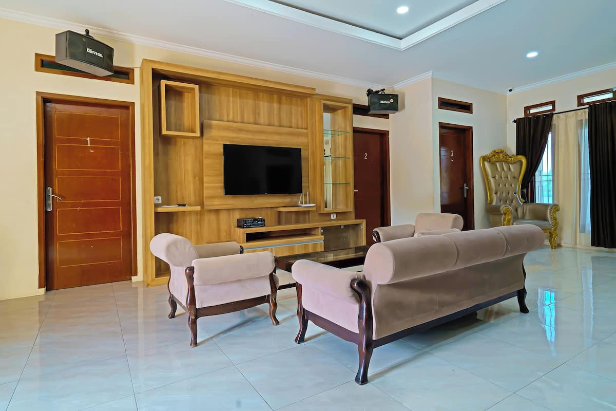 A spacious living room with a large flat-screen TV, two sofas, and a wooden entertainment unit.