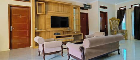Amplia sala de estar con un televisor de pantalla plana grande, dos sofás y un mueble de entretenimiento de madera.