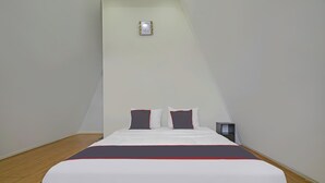 A neatly made bed with white and dark bedding, a red accent, and a nightstand with a lamp. - Collection O 92634 Villa Ds (Rancakalong)