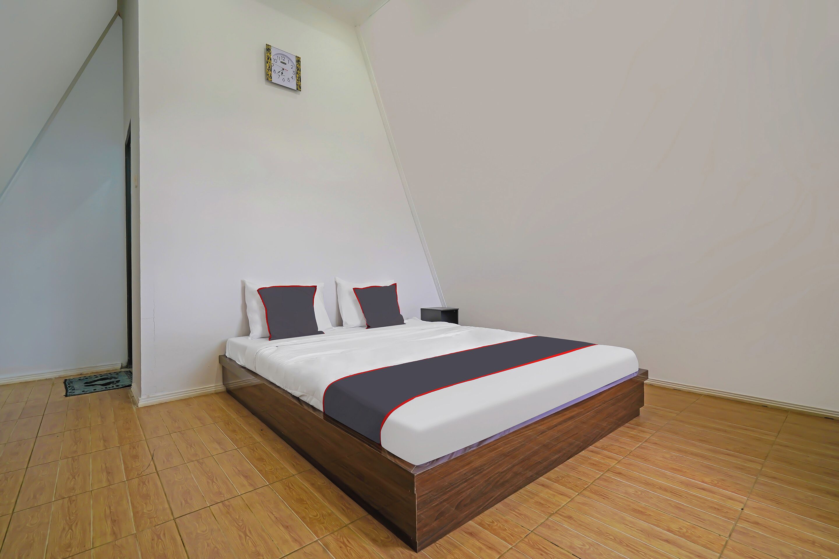 Un dormitorio con cama de madera, paredes blancas y suelo de baldosas.