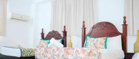 A bedroom with a wooden bed, floral bedding, and a window with curtains.