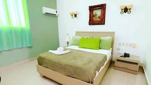 Un dormitorio con cama, mesita de noche, aire acondicionado instalado en la pared y un marco de fotos.